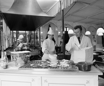 885004 Afbeelding van het besuikeren van de net gebakken poffertjes in de poffertjeskraam van Victor Consael (Neude, ...
